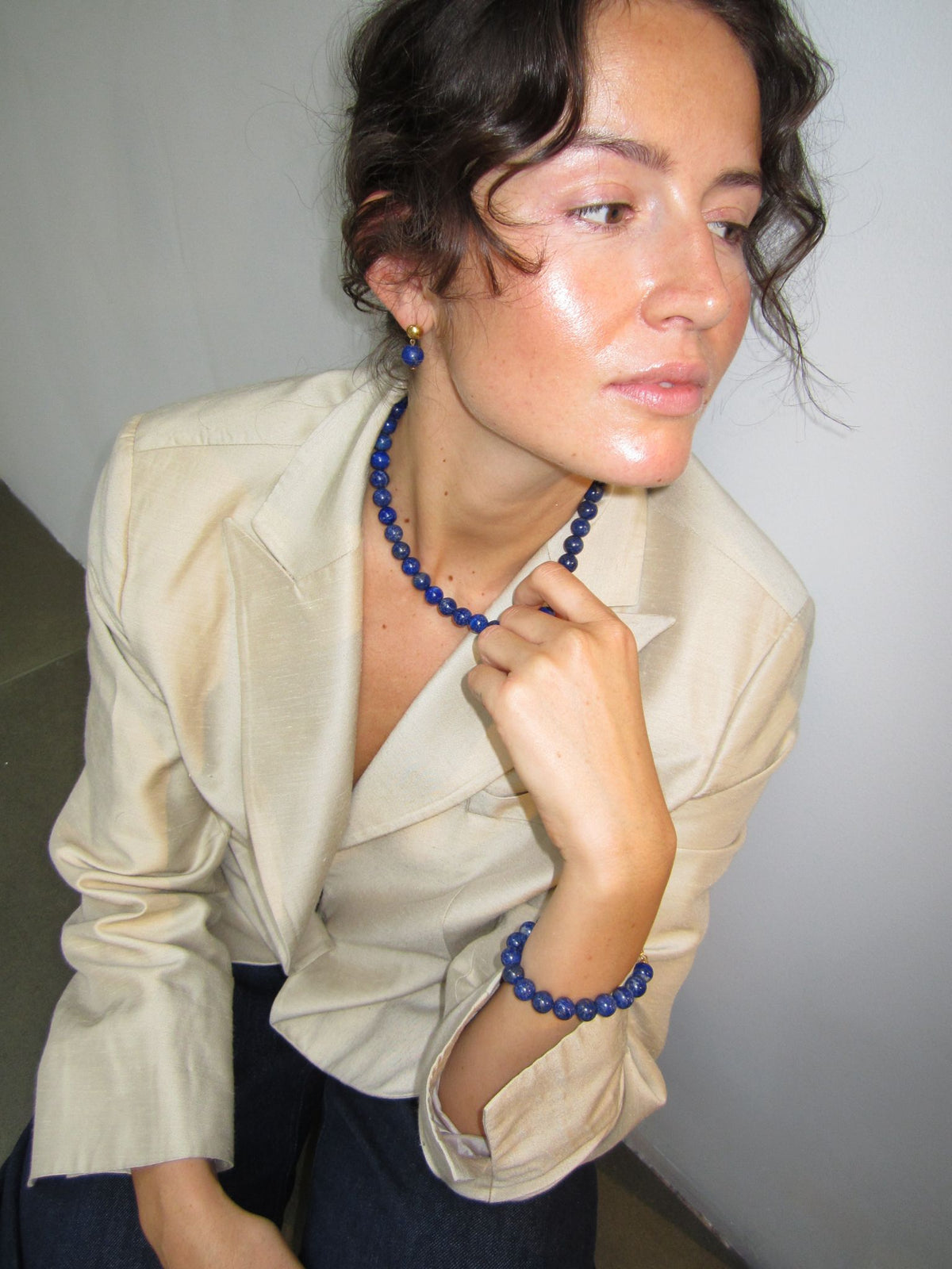 Blue lapis lazuli bead necklace and bracelet worn with a beige blazer