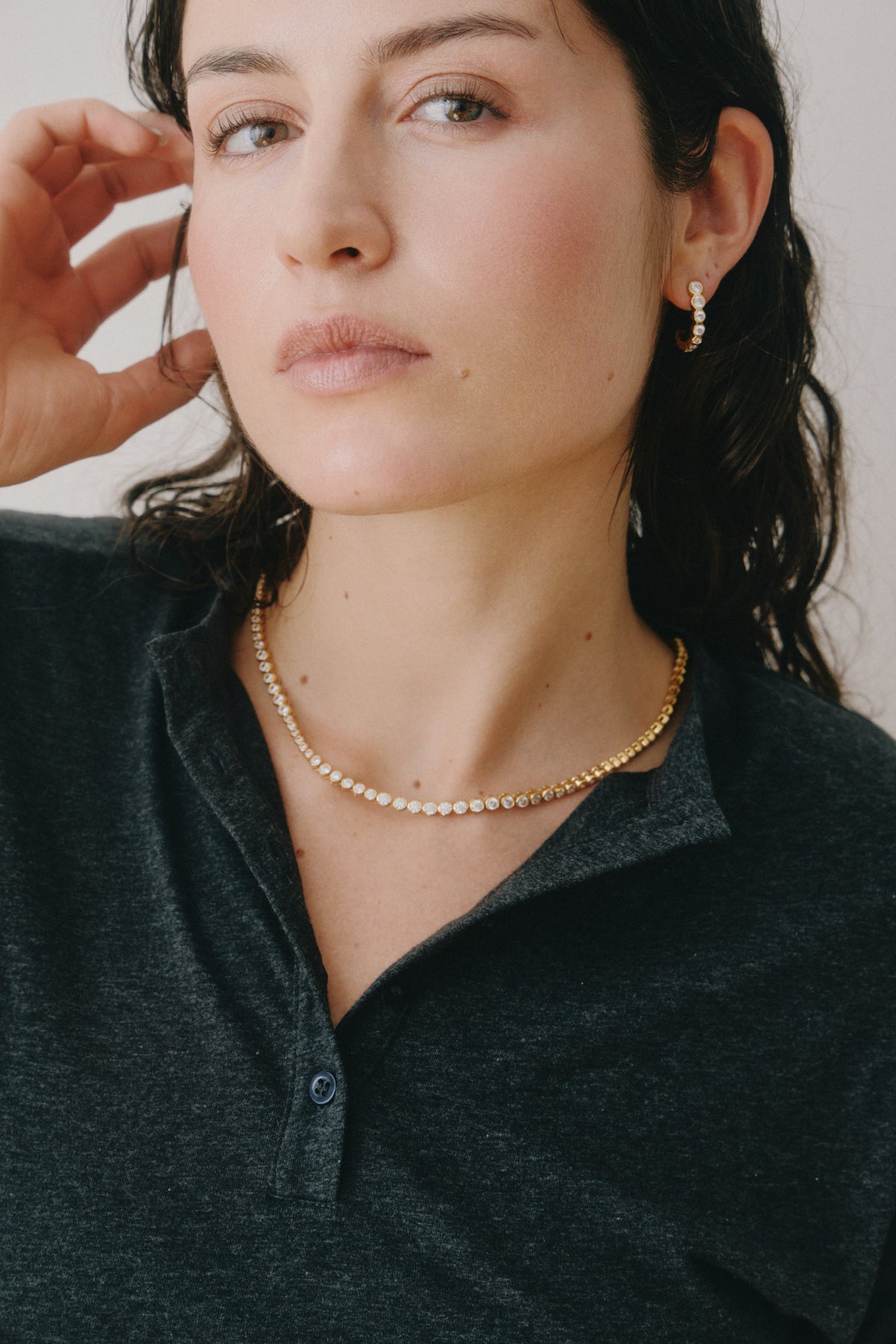 Gold tennis necklace worn with a dark knit polo