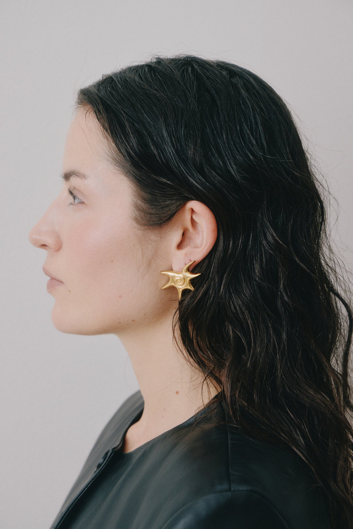Gold star earring worn in profile